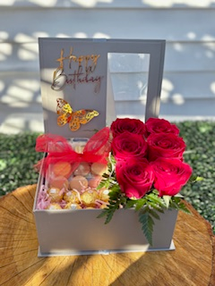 Deluxe gray gift box that includes vibrant red roses, fresh greens, in a beautiful arrangement with a chocolate gift surprise and delicious macarons that fill up a big portion of the box. Gold Happy Birthday Emblem and Butterfly add a special touch of elegance to this lovely gift.