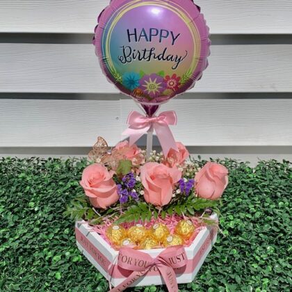 Birthday balloon in a wood container with roses and chocolates.